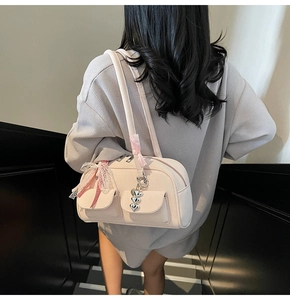 Detail of light pink Boston bag with lace bows, heart charms and ribbon accents