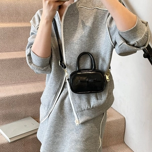 Detail of a mini black glossy crossbody bag with a bow and adjustable strap for kids