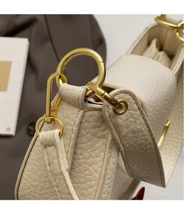 Detailed close-up of cream lychee-textured leather with golden hardware and metal hooks