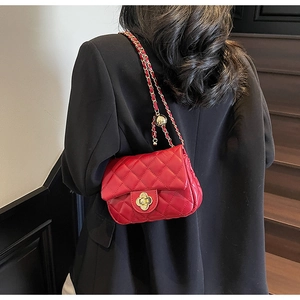 Detailed view of red quilted leather bag with gold flower clasp on black blazer