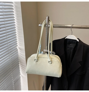 Detail of beige lychee leather Boston bag with silver rings hanging on a rack