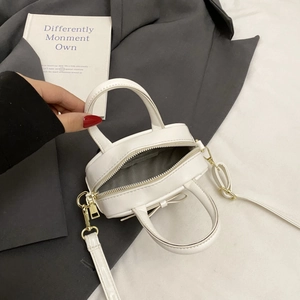 Close-up of a white mini handbag with a bow detail on textured grey suit background