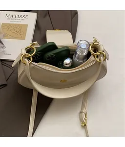 Detail of off-white crescent bag showing spacious interior for phones and perfume
