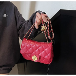 Detail of red quilted leather bag featuring a gold floral twist lock and metal chain strap