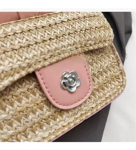 Détail du sac en paille tissée avec bordure rose et boucle en métal fleur argentée