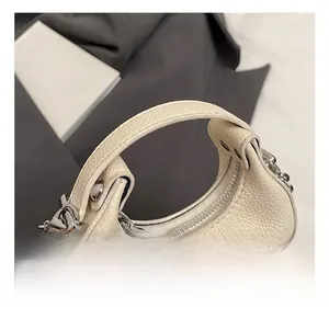 Detail of off-white pebble leather texture and silver hardware on the crescent bag