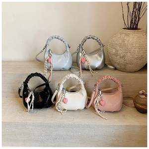 Minimalist half-moon handbags in five colors displayed on stone steps with heart charm