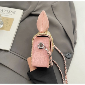Détail d'un sac bandoulière en paille rose avec nœud en cuir et bandoulière en chaîne