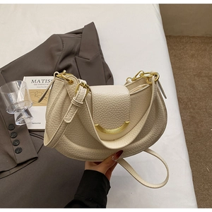 Detailed macro view of cream crescent bag featuring lychee grain leather and gold hardware