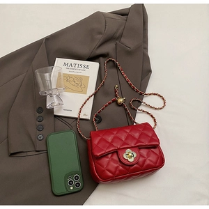 Detail of red quilted bag featuring a golden flower clasp and chain on a brown blazer