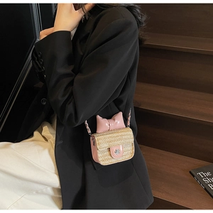 Détail du sac bandoulière en paille rose avec fermoir fleur et chaîne élégante