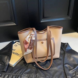 Beige tote bag with brown trim and bear print scarf on a black leather jacket background