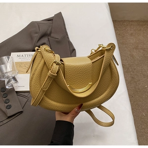 Detail of yellow lychee leather saddle bag with gold hardware on a fashion background