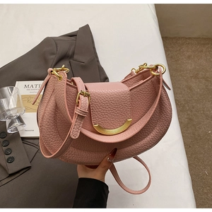 Detail of pink lychee grain leather crescent bag with golden buckle on city style background