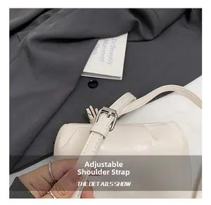 Close-up of adjustable shoulder strap with silver buckle on cream faux leather bag