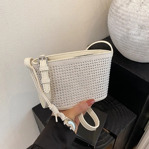 Cream rhinestone baguette bag with silver studs and adjustable strap in a stylish hand-held shot