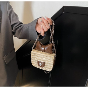 Détail d'un sac en paille fait main avec nœud en cuir marron et fermoir fleur en métal