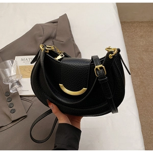 Detail of black pebbled leather saddle bag with gold crescent buckle and adjustable strap
