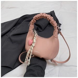 Detailed view of pink PU leather handbag with heart pendant and woven tassel on blazer