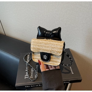 Détail du sac bandoulière en paille tissée avec nœud noir et boucle fleur camélia