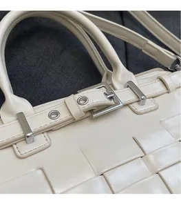 Macro detail of beige woven bucket bag featuring silver metal buckle and strap