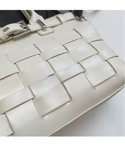 Close-up of cream white woven leather handbag with wide straps and metal buckle detail