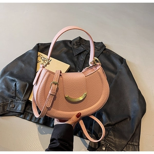 Close-up of pink lychee grain leather saddle bag with crescent gold buckle and long strap