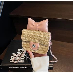Détail du sac à bandoulière en paille avec nœud en cuir rose et fermoir camélia en métal