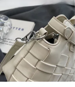 Close-up of silver metal hooks and woven faux leather texture on cream bucket bag
