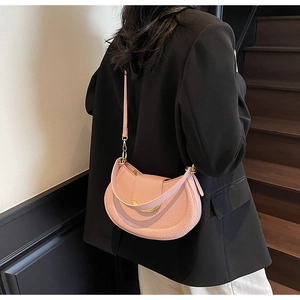 Detail of pink lychee leather crescent bag with golden buckle on black blazer