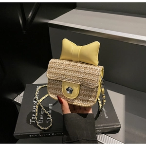 Détail du sac bandoulière en paille avec nœud en cuir jaune et fermoir fleur en métal