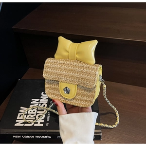 Détail du mini sac bandoulière en paille avec grand nœud jaune et fermoir fleur en métal
