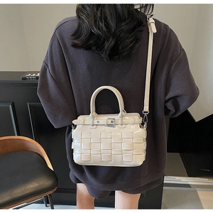 Detail of hand-woven beige PU leather handbag with elegant buckle and detachable strap