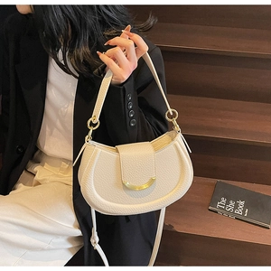 Detailed close-up of white pebble leather saddle bag with gold metal buckle on stairs
