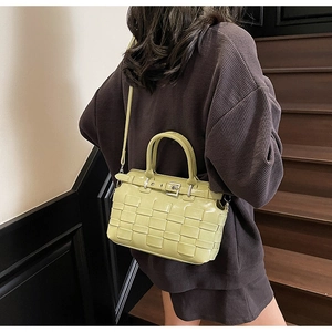 Detailed view of woven pattern and metallic buckle on light green crossbody bag