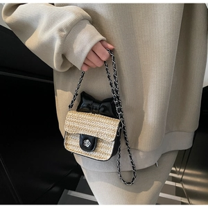 Détail du sac en paille tressée avec nœud noir et fermoir métallique en fleur de camélia