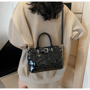 Detailed view of black woven leather handbag with adjustable strap shown on model