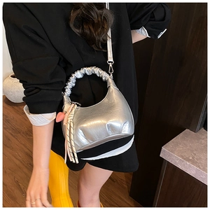 Silver metallic crescent bag detail with pleated handle and heart charm on a model