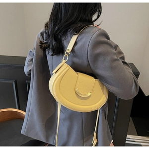 Detail of yellow crescent saddle bag with pebble texture leather and gold hardware