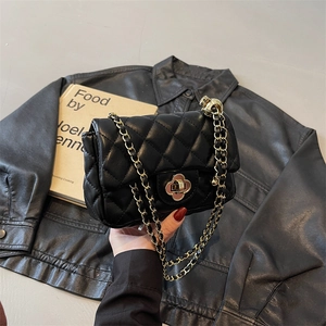 Chic black quilted chain bag with clover lock and leather woven strap in hand