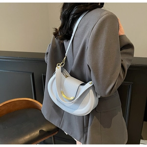 Detailed texture of light blue pebble leather on a crescent saddle bag with gold metal buckle