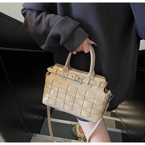 Detailed close-up of a beige woven crossbody bag with stylish silver buckle and leather strap
