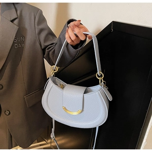 Close-up of light blue saddle bag with lychee grain leather and golden metal clasp