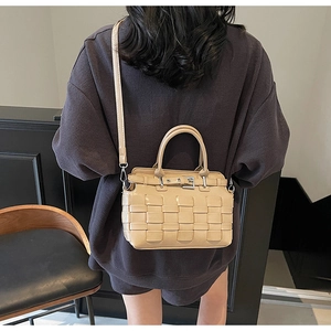 Detail of beige hand-woven shoulder bag showing texture and adjustable strap on model
