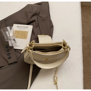 Detail view of the cream crescent bag interior with three functional compartments and gold hardware