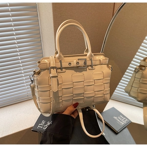 Detail of cream-white woven texture and adjustable strap on a leather shoulder bag