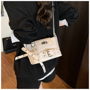 Détail du sac bandoulière crème avec sangles à œillets argentés et boucle sur mannequin
