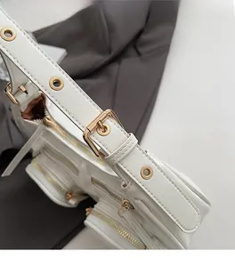 Detail of white PU leather shoulder bag with gold hardware and multi-pocket zippers