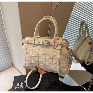 Close-up of cream woven handbag showing leather texture, dual handles and silver buckles