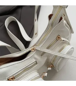 Detailed close-up of white leather multi-zipper bag with smooth gold-toned hardware